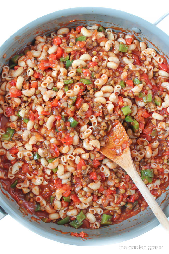 Mushroom lentil goulash in a skillet with wooden spoon