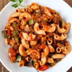 Overhead view of vegan goulash on a white serving plate with spoon