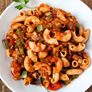 Overhead view of vegan goulash on a white serving plate with spoon