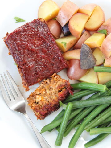 Vegan gluten-free meatloaf on a plate with green beans and potatoes
