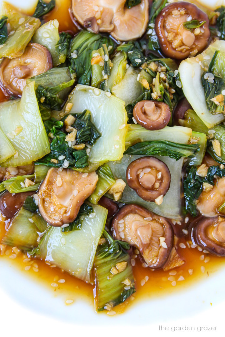 Close up view of garlic bok choy with shiitake mushrooms on a white plate