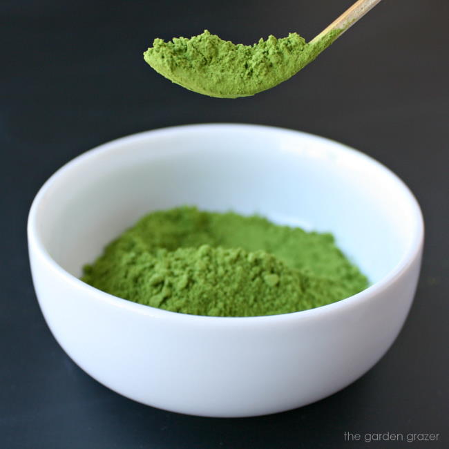 Bowl of organic matcha powder with a bamboo scoop