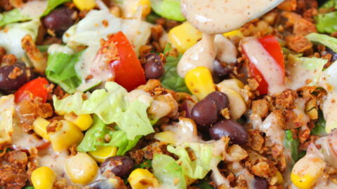 Vegan taco salad in a white bowl with dressing on a spoon