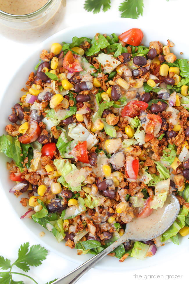 Large white bowl with vegan taco salad and dressing on the side