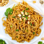 Hoisin peanut noodles on a white plate with chopsticks