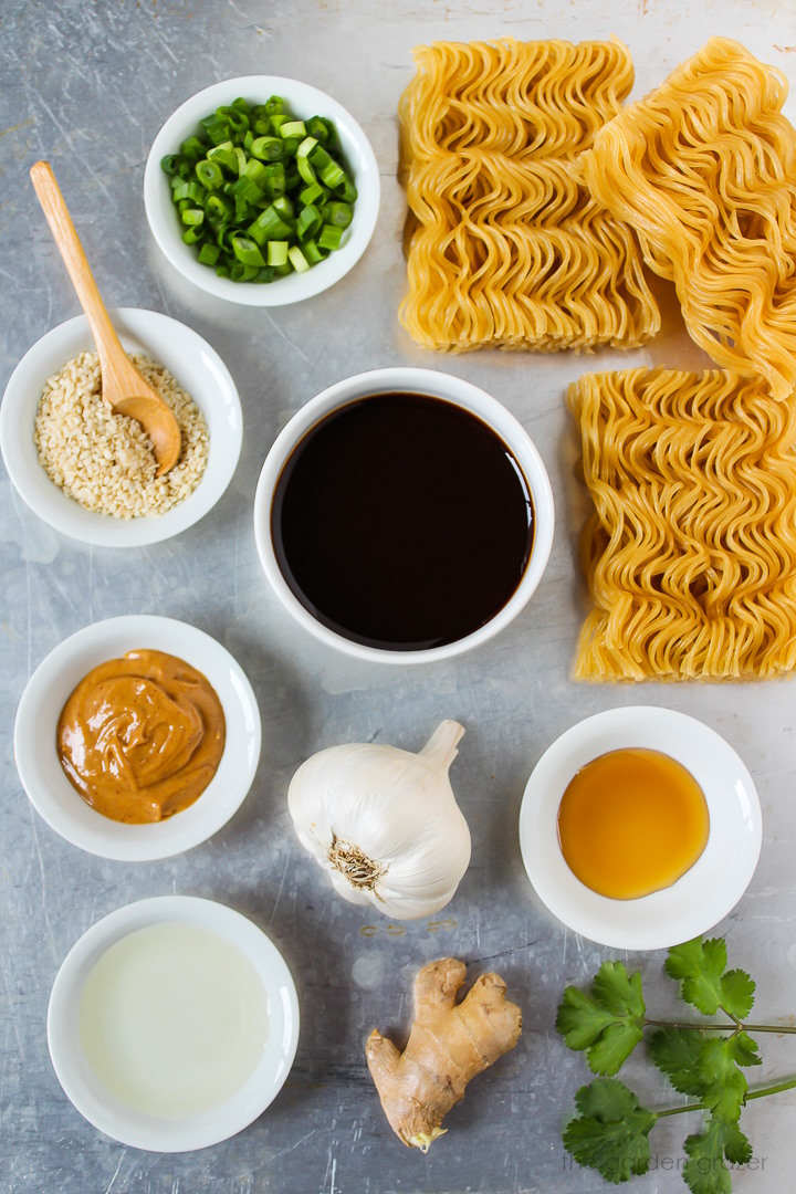 Ramen cakes, green onions, garlic, ginger, peanut butter, and vinegar ingredients laid out on a metal tray