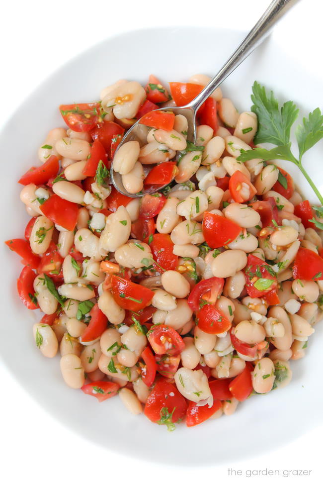 Small bowl of white bean tomato herb salad with spoon