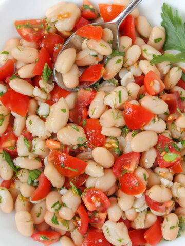 White bean salad with tomato in a white bowl