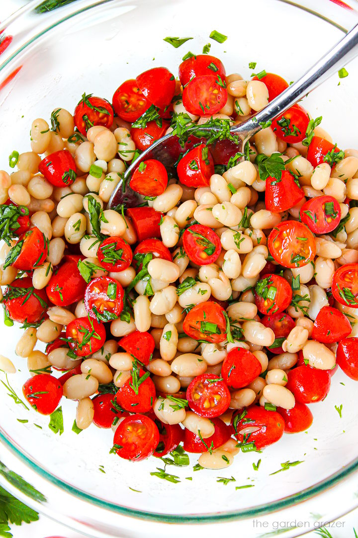 Overhead view of white bean tomato salad mixed together in a large glass bowl