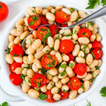 White bean tomato salad in a serving bowl with fresh herbs and vinegar dressing