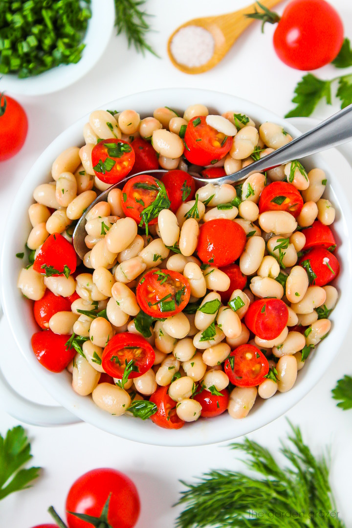 White bean tomato salad in a serving bowl with fresh herbs and vinegar dressing