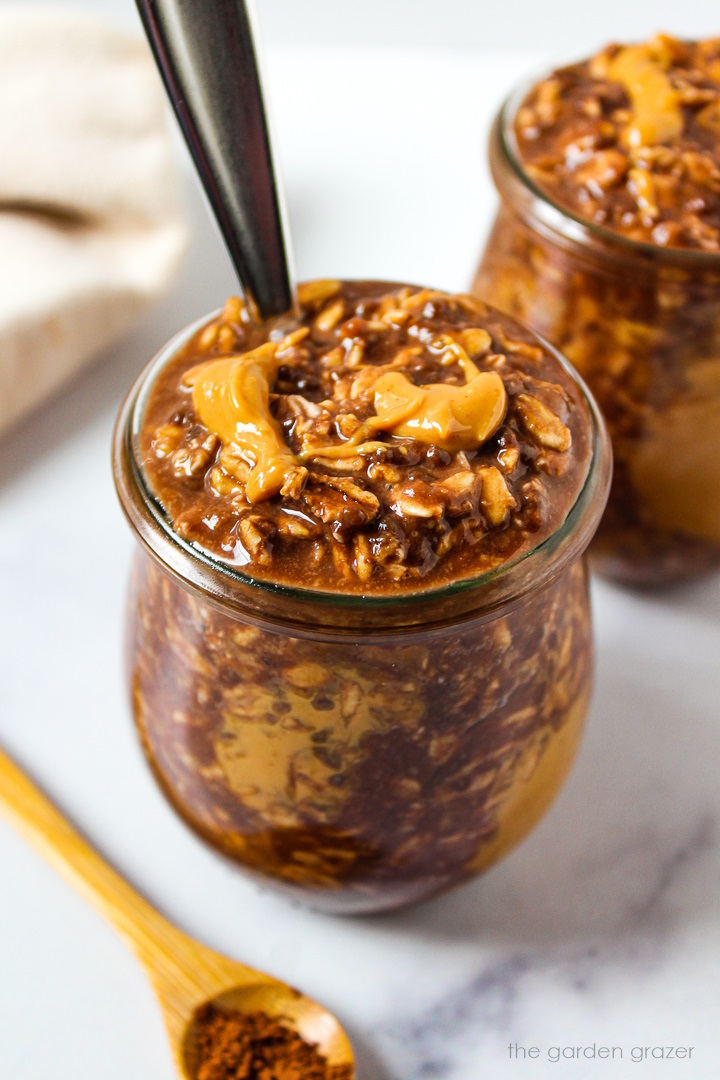 Chunky monkey overnight oats served in small glass jars with a drizzle of peanut butter