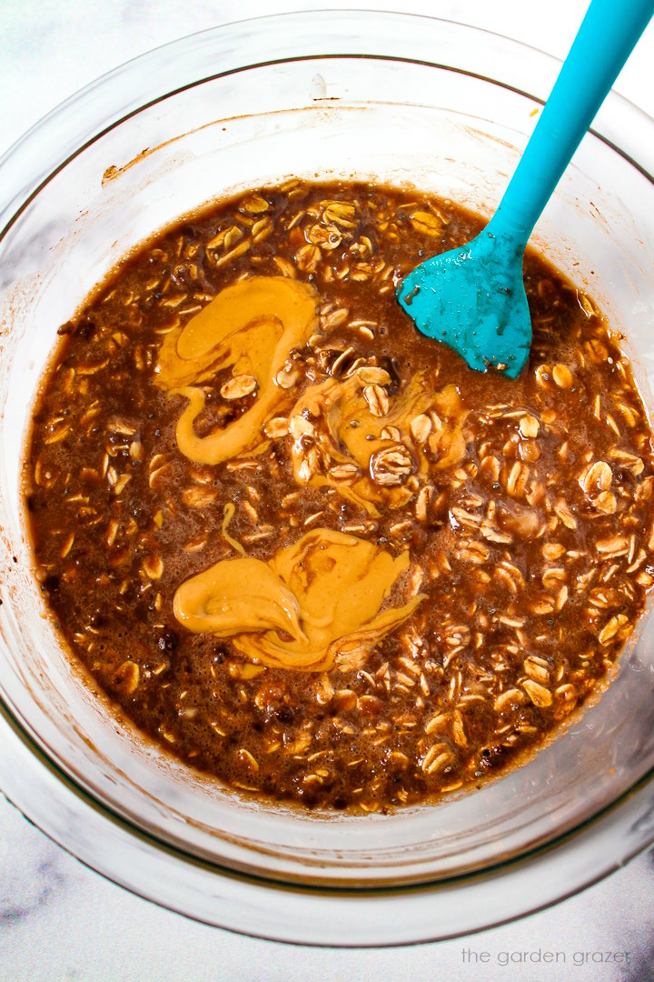 Chunky monkey overnight oat ingredients mixed together in a glass bowl with spatula