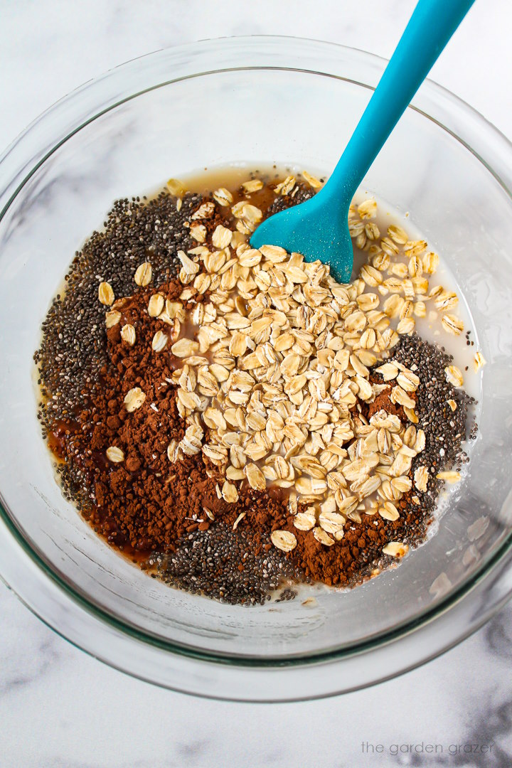 Overhead view of preparing overnight oat ingredients in a glass bowl before mixing together