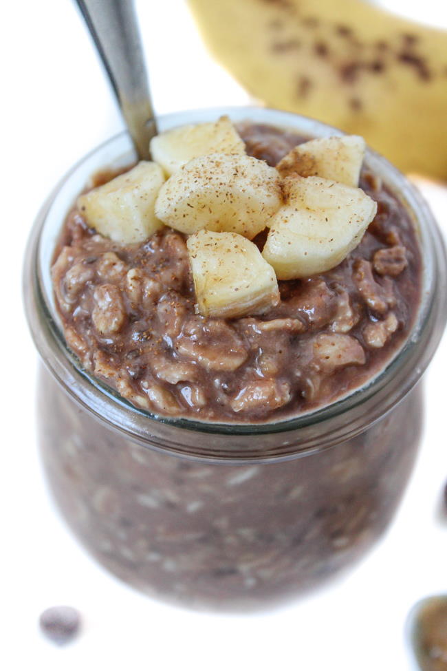 Overnight oats in a small glass jar with banana, peanut butter, and chocolate