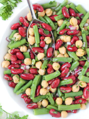 Three bean salad with oil-free vinegar dressing in a white bowl with spoon