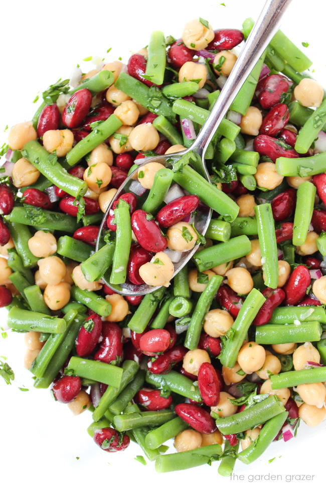 Vegan three bean salad in a glass bowl with spoon