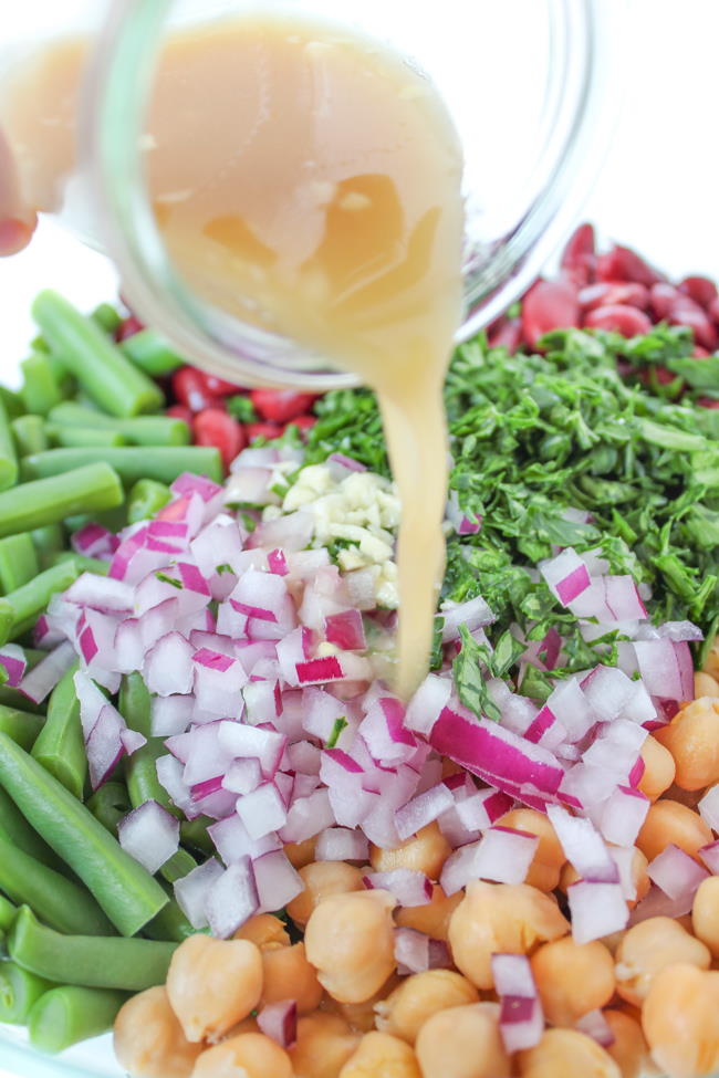 Preparation with vinegar dressing being poured on top of salad