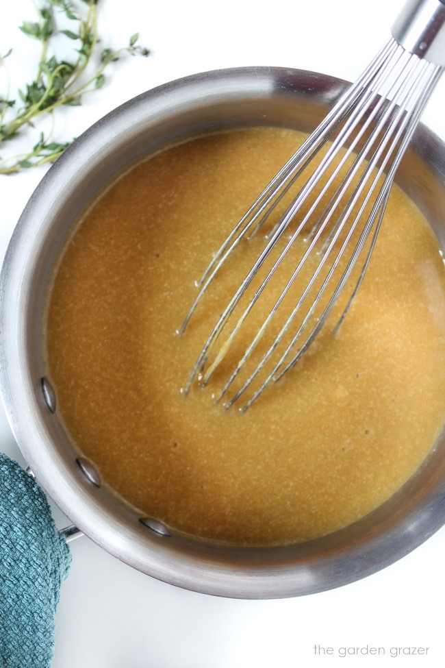 Vegan gravy cooking in a saucepan with metal whisk