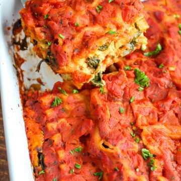 Metal spatula lifting out a piece of vegan lasagna from large baking dish