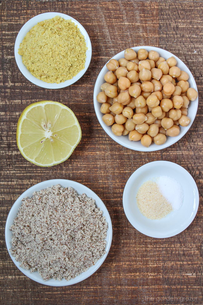 Chickpeas, almond flour, nutritional yeast, and fresh lemon on a wooden table