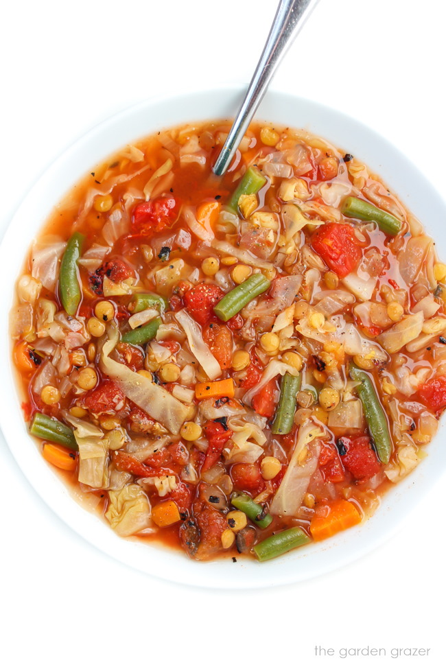 Vegan lentil and cabbage soup in a white bowl with spoon