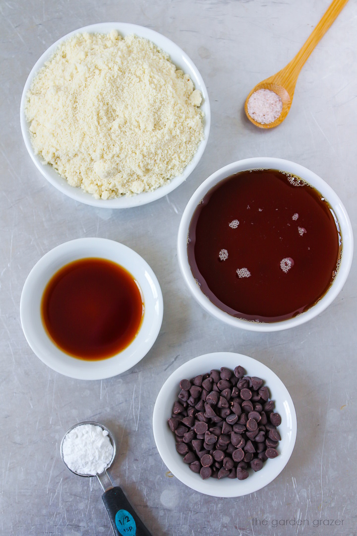 Flour, maple syrup, vanilla extract, baking powder, and chocolate chip ingredients laid out on a metal tray