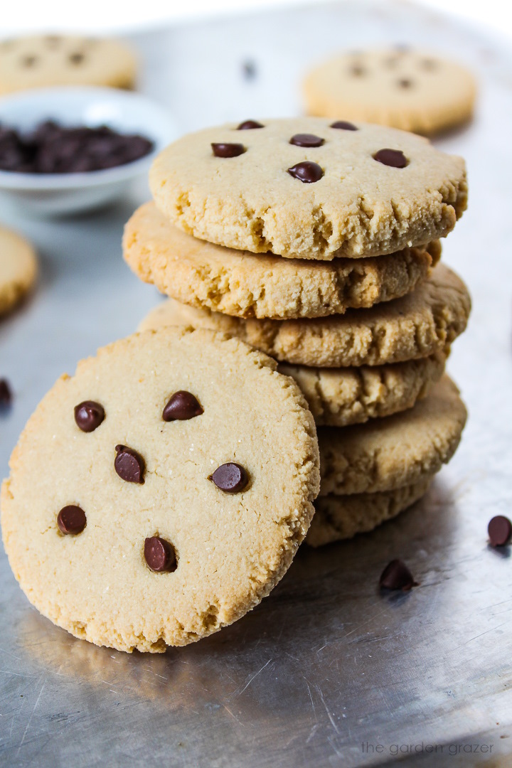 A stack of vegan almond maple cookies with chocolate chips on a sheet pan
