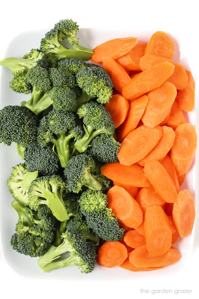 Fresh broccoli florets and sliced carrots ingredients on a white plate
