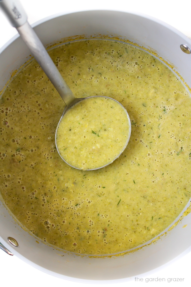 Blended soup cooking in a stockpot with metal ladle