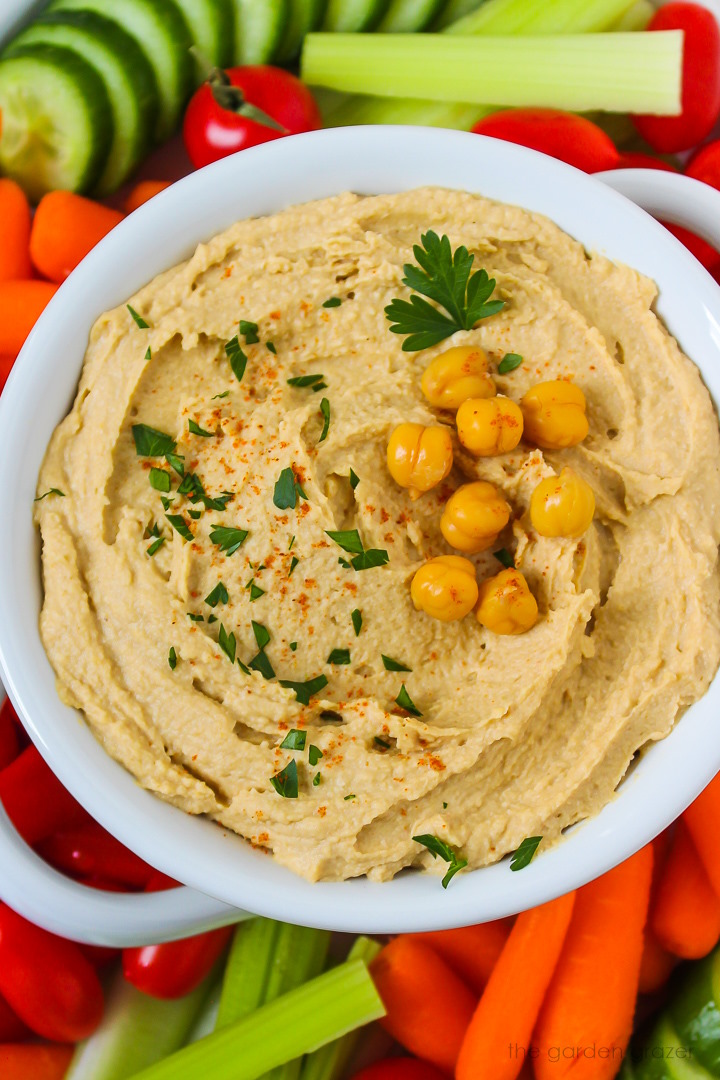 Close up view of oil-free hummus in a white bowl topped with parsley