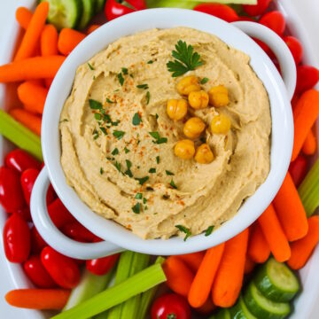 Overhead view of a veggie platter with a bowl of homemade oil-free hummus in the middle