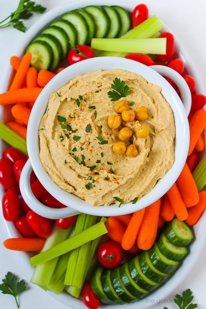 Overhead view of a veggie platter with a bowl of homemade oil-free hummus in the middle