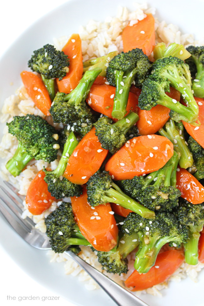 Vegan teriyaki and carrots with brown rice in a white bowl with fork