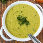 Vegan broccoli potato soup in a white serving bowl garnished with fresh dill