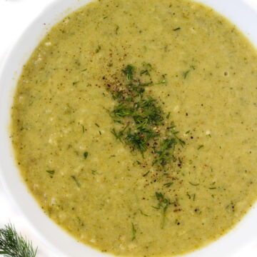 Healthy vegan broccoli potato soup in a white bowl with fresh dill