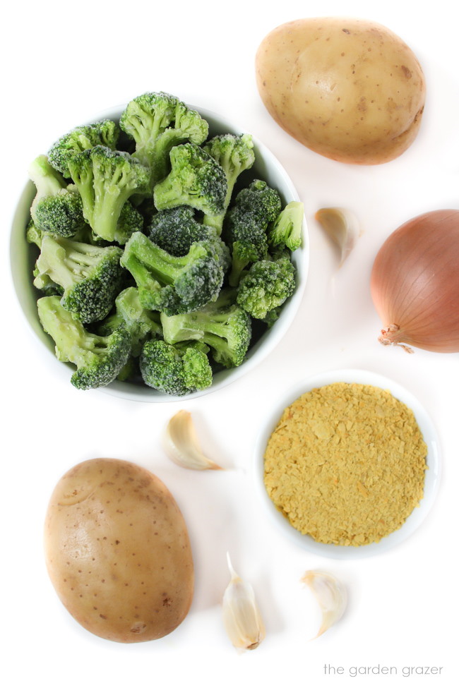 Frozen broccoli, potato, onion, garlic, and nutritional yeast ingredients on a white table