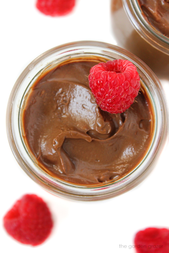 Dairy-free chocolate avocado mousse topped with raspberry in a glass jar