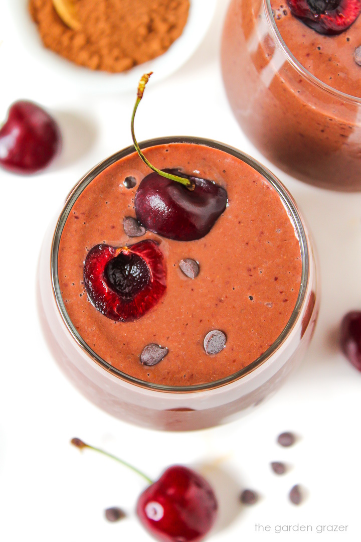 Overhead view of chocolate cherry smoothie in a glass topped with fresh cherry