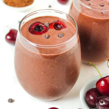 Chocolate cherry smoothie with almond and banana in a serving glass with fresh cherries