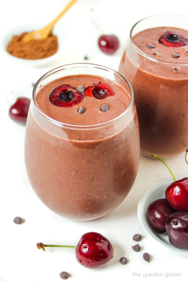 Chocolate cherry smoothie with almond and banana in a serving glass with fresh cherries