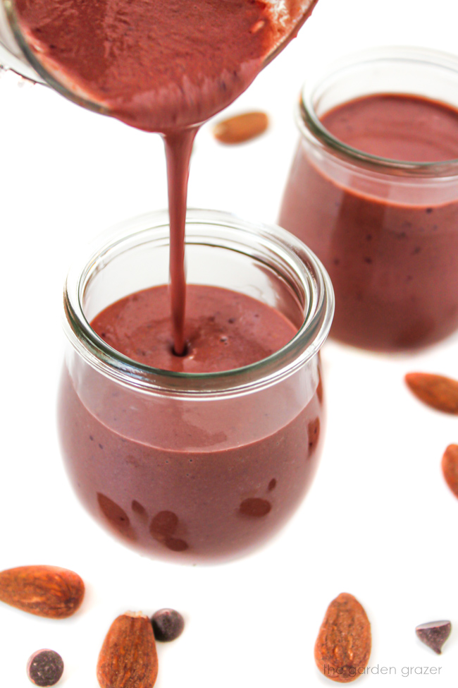 Pouring a chocolate cherry almond smoothie into a small glass