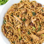 Vegan shiitake mushroom garlic noodles in a white bowl with fork