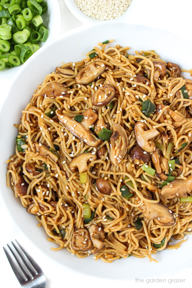 Vegan shiitake mushroom garlic noodles in a white bowl with fork