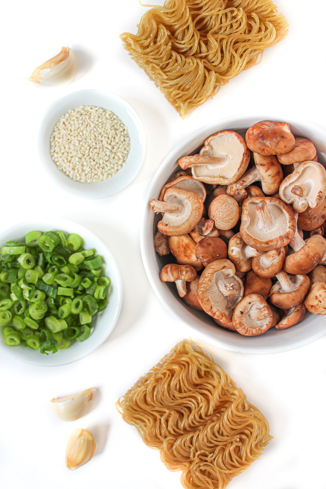 Mushrooms, ramen noodles, green onions, and garlic ingredients on a white table