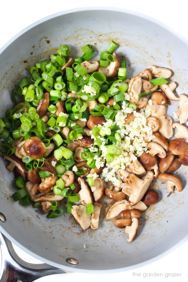 Cooking shiitake mushrooms, green onions, and garlic in a skillet