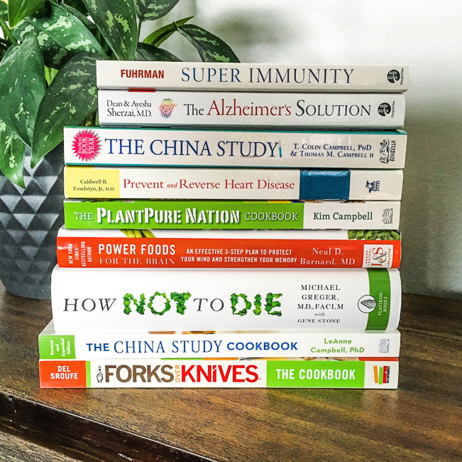 A collection of plant-based health books stacked on a bookshelf