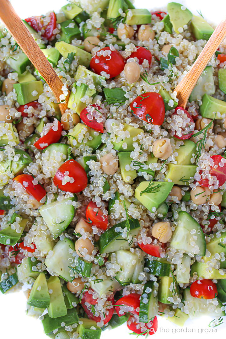 Dill Quinoa Salad with lemon, avocado, and tomato in a bowl with bamboo serving spoons