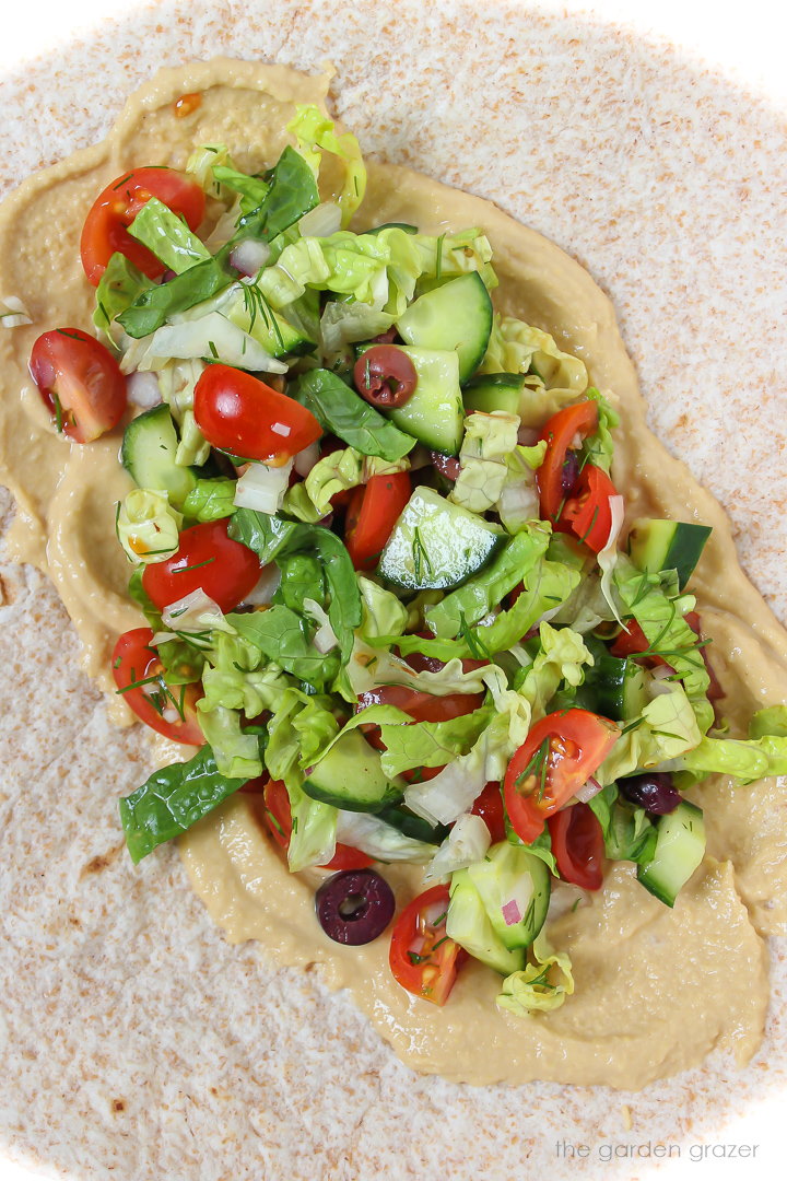 Open-faced wrap with hummus and Greek salad ingredients