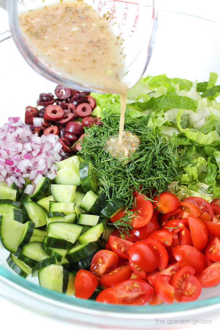 Dressing being poured over salad ingredients in a bowl